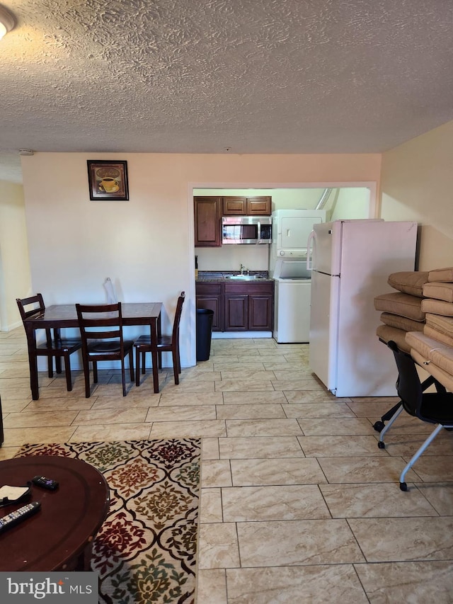 interior space featuring stacked washing maching and dryer, wood tiled floor, and a textured ceiling