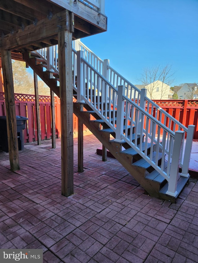 view of patio / terrace featuring fence and stairs