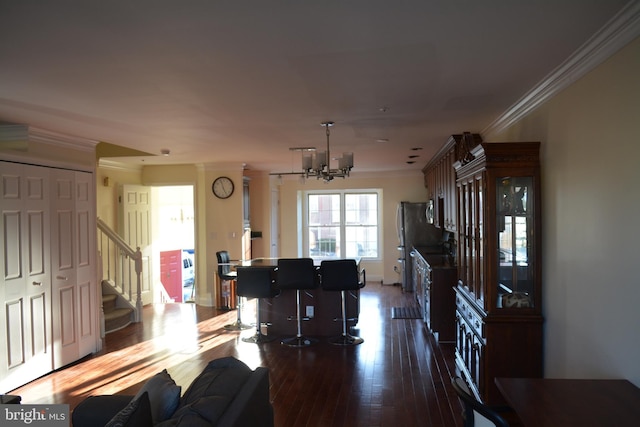 living area featuring stairway, an inviting chandelier, ornamental molding, wood finished floors, and baseboards