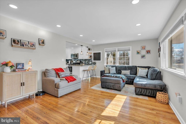 living room featuring baseboards, recessed lighting, and light wood-style floors