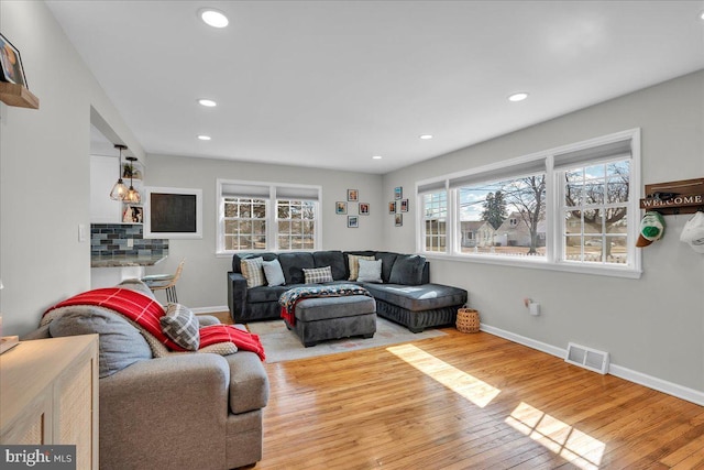 living room featuring recessed lighting, wood-type flooring, visible vents, and baseboards