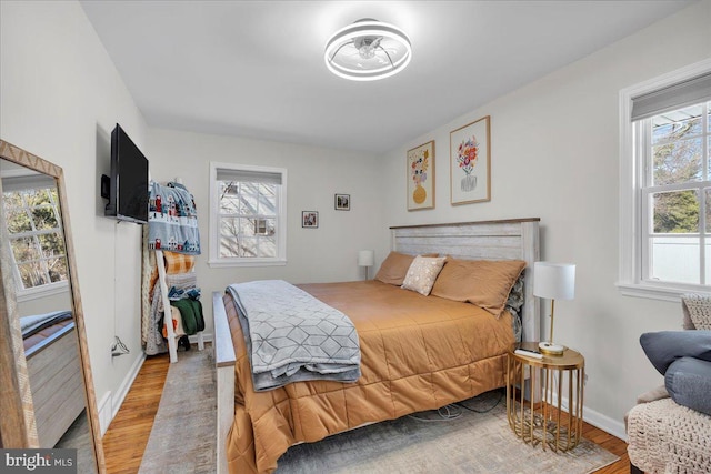 bedroom featuring light wood finished floors, multiple windows, and baseboards