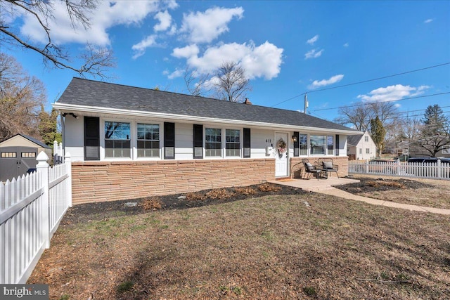 back of house featuring stone siding, a patio area, fence, and a lawn