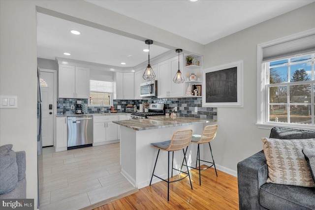 kitchen featuring stainless steel appliances, a breakfast bar, a peninsula, a sink, and open floor plan