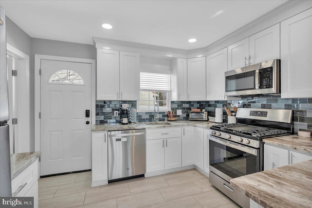 kitchen featuring appliances with stainless steel finishes, a sink, white cabinetry, and tasteful backsplash