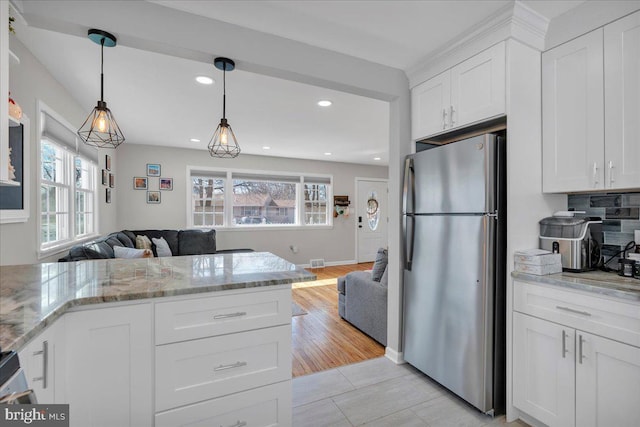 kitchen with a healthy amount of sunlight, white cabinets, open floor plan, and freestanding refrigerator