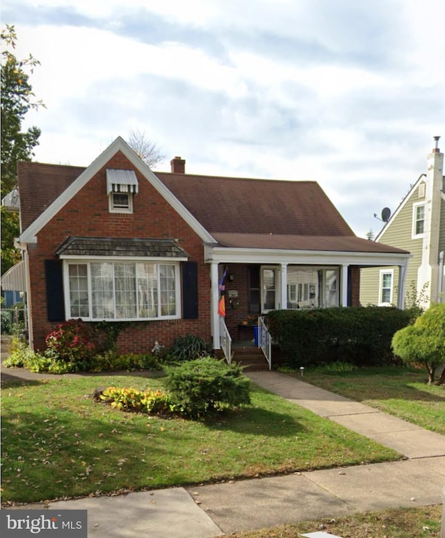 view of front of home with brick siding, a chimney, and a front lawn