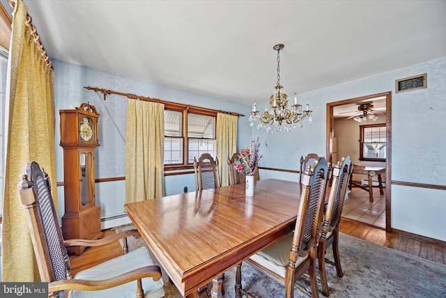 dining space featuring visible vents, baseboard heating, hardwood / wood-style floors, and ceiling fan with notable chandelier