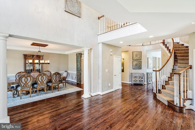 entryway with wood finished floors, baseboards, stairs, ornate columns, and crown molding