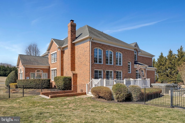 exterior space with brick siding, a yard, a chimney, and fence