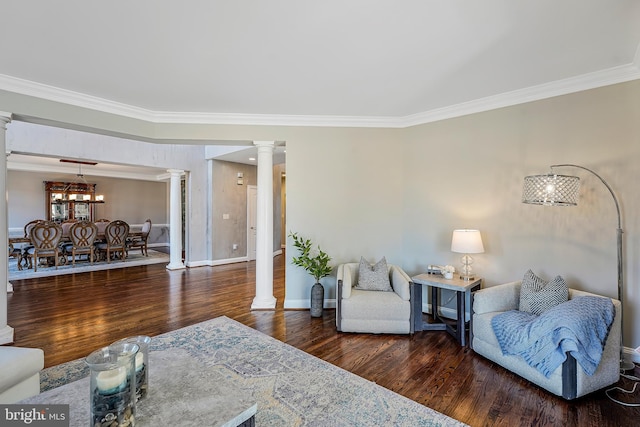 living room with ornamental molding, wood finished floors, decorative columns, and baseboards