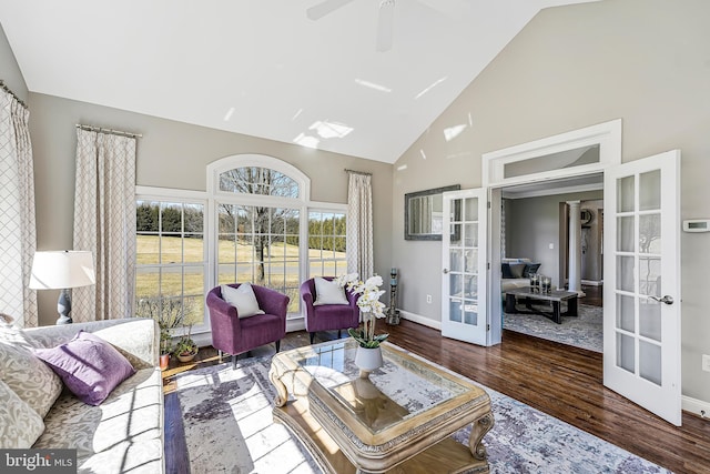 living area with baseboards, high vaulted ceiling, wood finished floors, and french doors