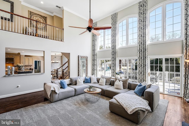 living area with stairs, ceiling fan with notable chandelier, crown molding, and wood finished floors