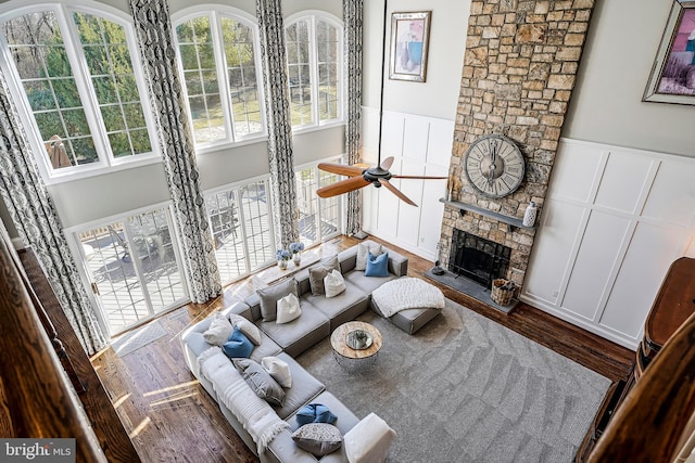 sunken living room with a fireplace, a decorative wall, a high ceiling, and wood finished floors