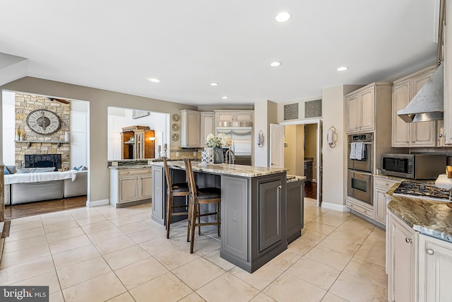 kitchen featuring light tile patterned floors, a center island with sink, appliances with stainless steel finishes, and a kitchen breakfast bar