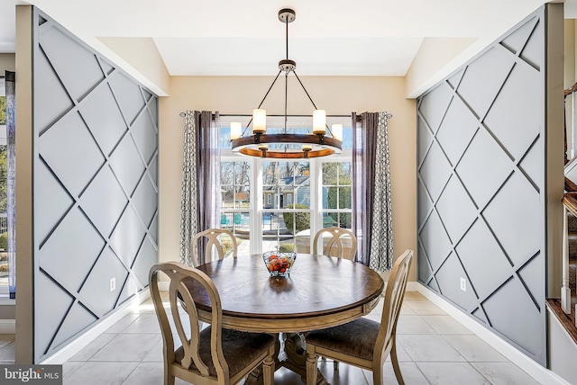 dining room with light tile patterned floors, an accent wall, baseboards, and an inviting chandelier