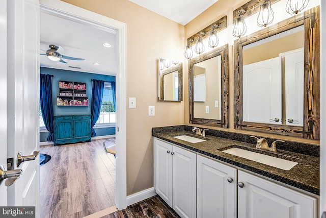 bathroom with ceiling fan, baseboards, a sink, and wood finished floors