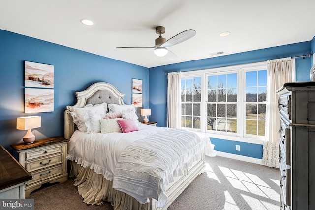 carpeted bedroom with ceiling fan, multiple windows, visible vents, and baseboards