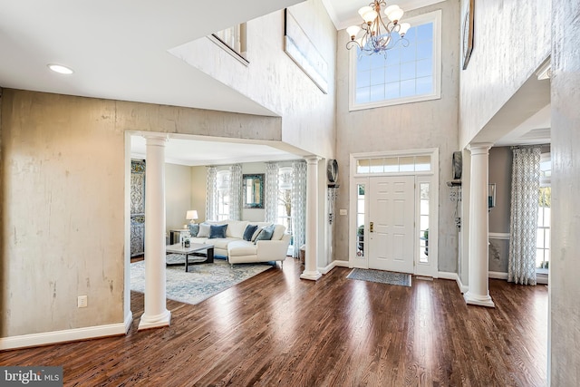 entryway featuring decorative columns, baseboards, and wood finished floors