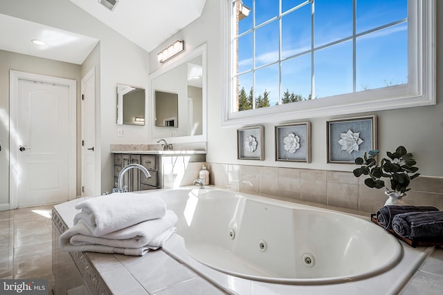 full bathroom featuring visible vents, a tub with jets, tile patterned floors, vaulted ceiling, and vanity