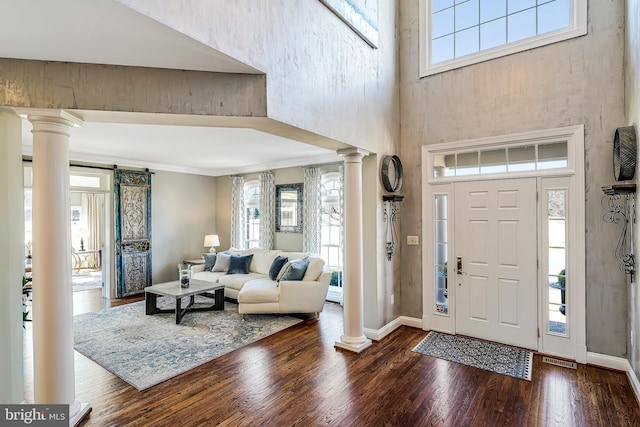 foyer entrance with ornate columns, plenty of natural light, ornamental molding, and wood finished floors