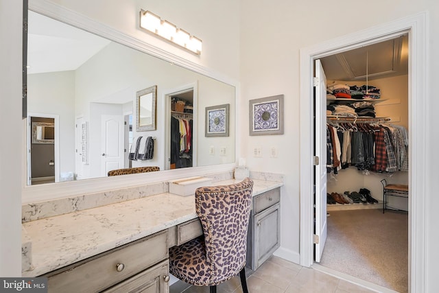 bathroom with a walk in closet, vanity, and tile patterned floors