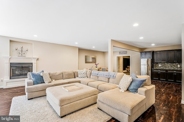 living room with a glass covered fireplace, dark wood-style flooring, and recessed lighting