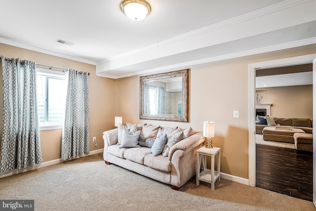 carpeted living area featuring ornamental molding, visible vents, a fireplace, and baseboards