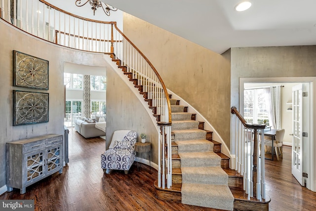 stairs with a towering ceiling, baseboards, and wood finished floors