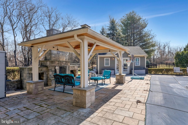 view of patio / terrace featuring an outbuilding, fence, a gazebo, and an outdoor living space with a fireplace