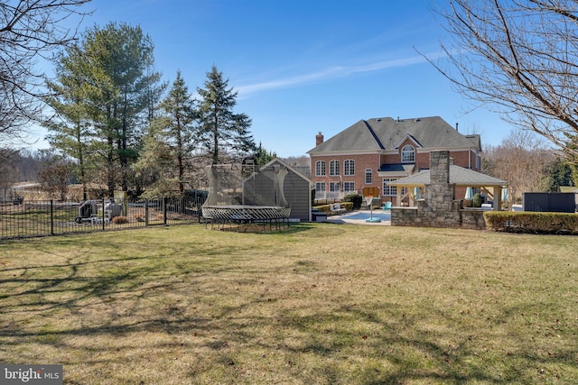 exterior space featuring a chimney, a trampoline, fence, a yard, and a patio area