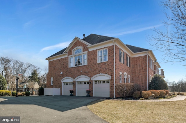 view of home's exterior featuring driveway, a garage, a lawn, fence, and brick siding