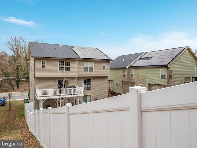 back of property featuring a fenced backyard and roof mounted solar panels