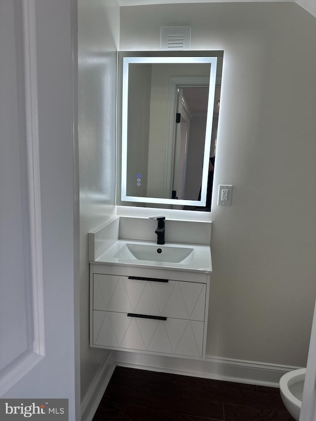 bathroom with visible vents, baseboards, wood finished floors, and vanity