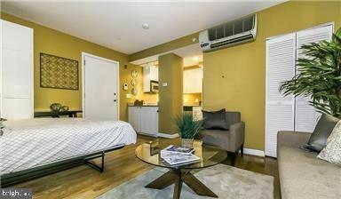 bedroom with a wall mounted air conditioner, wood finished floors, and baseboards