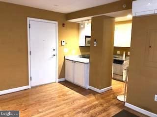 kitchen featuring white microwave, baseboards, dishwasher, and wood finished floors