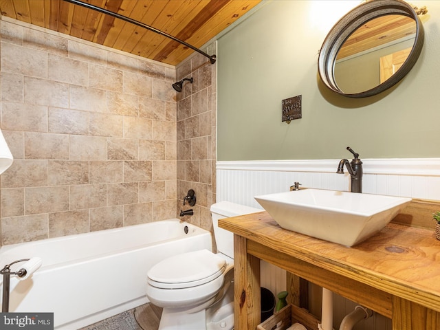 bathroom featuring toilet, wooden ceiling, a wainscoted wall, bathtub / shower combination, and a sink