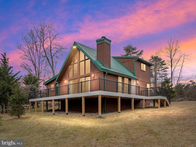 back of property with metal roof, a lawn, a chimney, and a wooden deck