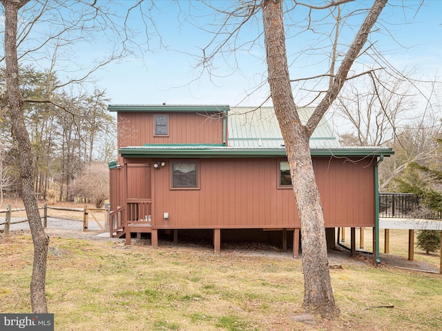 back of house featuring metal roof and a lawn