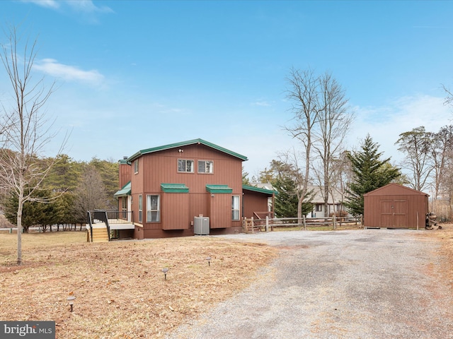 exterior space with a storage unit, an outdoor structure, fence, driveway, and a wooden deck