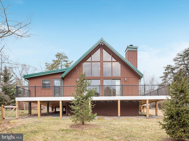 back of property featuring a yard, a carport, a chimney, and a wooden deck