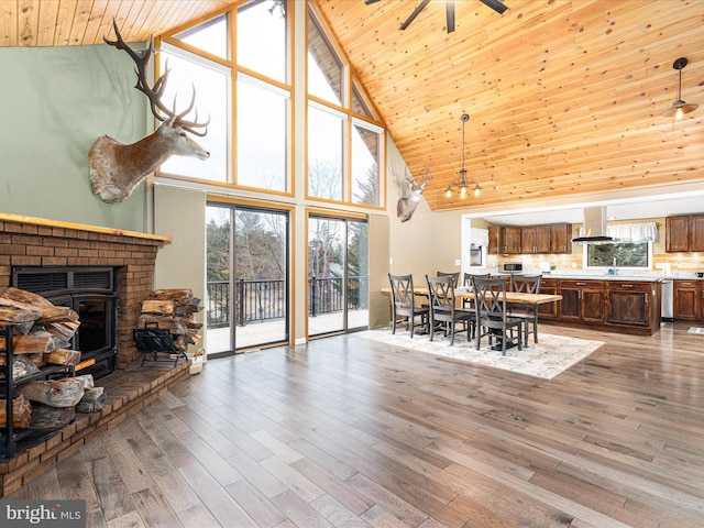 dining area featuring wooden ceiling, a brick fireplace, a wealth of natural light, and wood finished floors