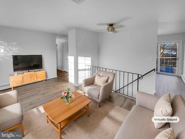 living area with ceiling fan, a baseboard radiator, and wood finished floors