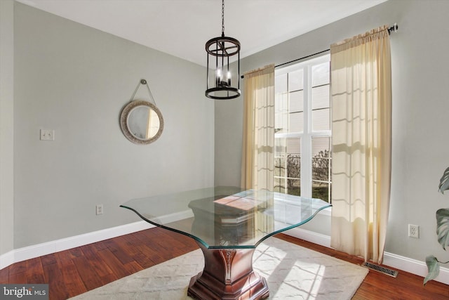 dining space with a wealth of natural light, a chandelier, baseboards, and wood finished floors