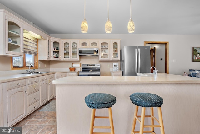 kitchen with stainless steel appliances, a breakfast bar, a sink, and light countertops