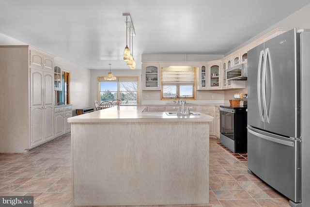 kitchen with stainless steel appliances, a sink, a center island, stone finish floor, and glass insert cabinets