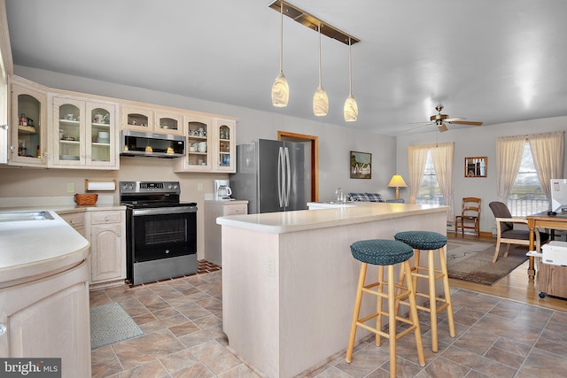 kitchen with a breakfast bar, stainless steel appliances, a sink, and light countertops