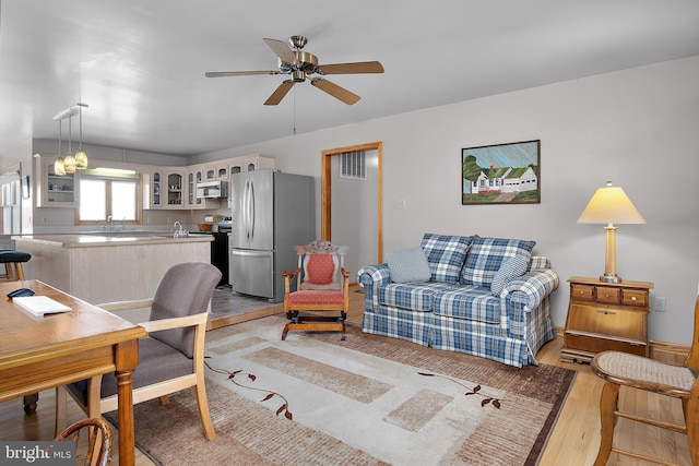 living room with light wood finished floors, ceiling fan, and visible vents