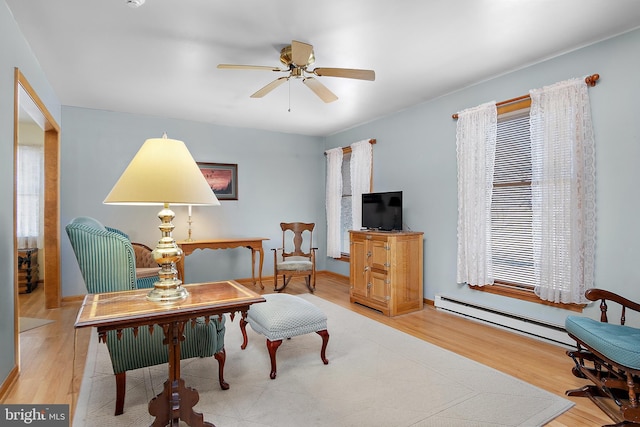 sitting room with a baseboard heating unit, ceiling fan, and wood finished floors