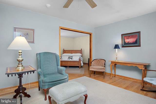 living area with ceiling fan, baseboards, and wood finished floors